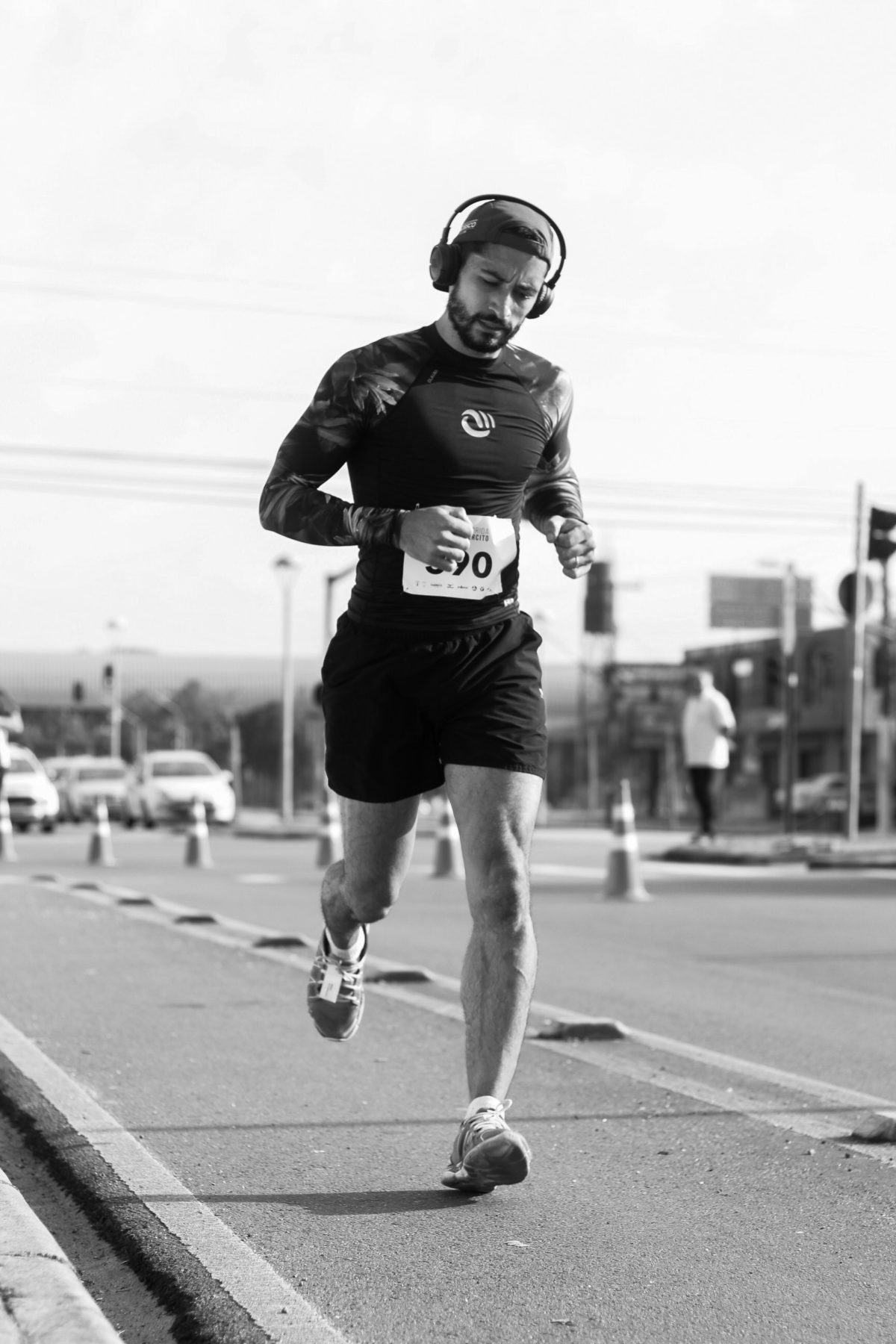 man wondering about consistency vs intensity running on a road and wearing headphones and shorts and a tshirt