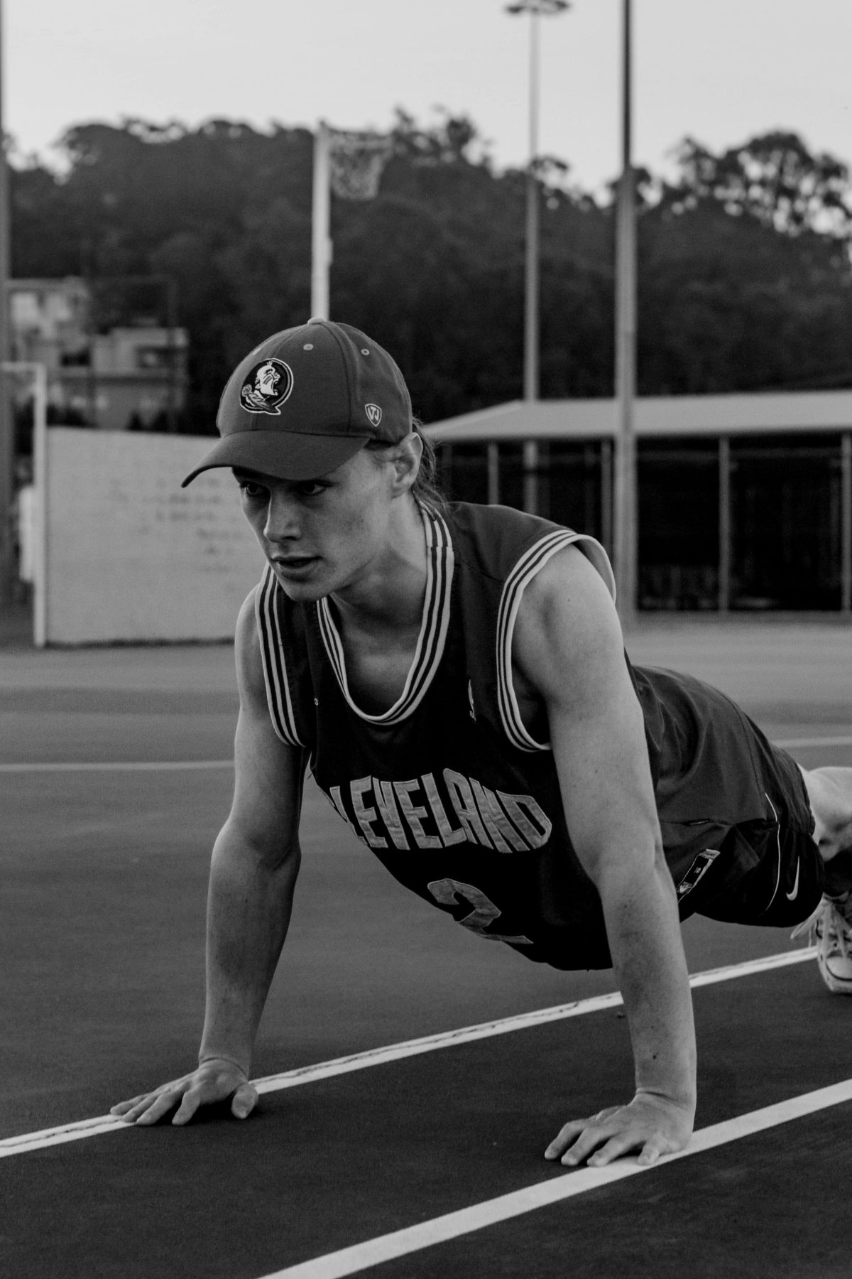 guy wearing cleveland singlet knowing how to do burpees on an athletic track