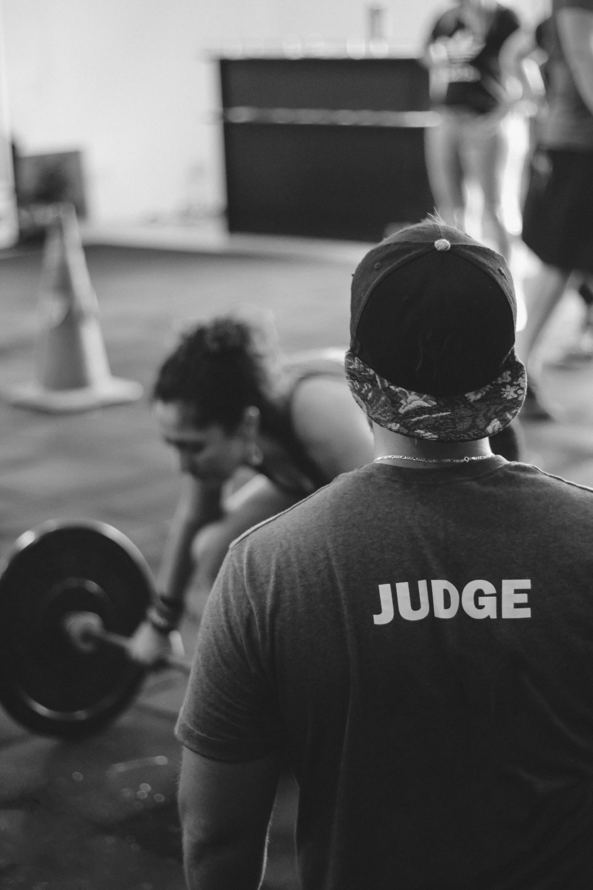 man in judge shirt looking for quality over quantity when woman deadlifts barbell