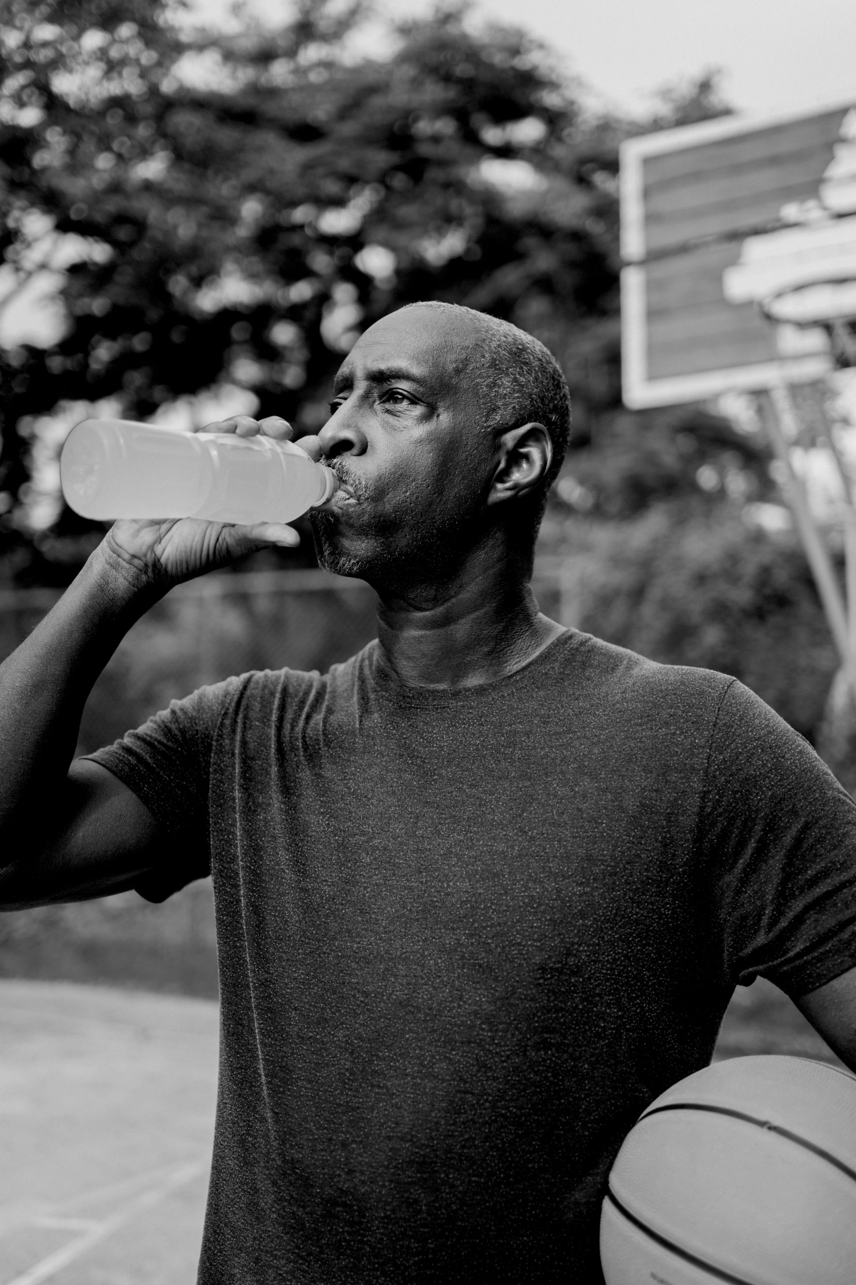 man holding basketball drinking out of bottle which is how to avoid heat stroke in the summer
