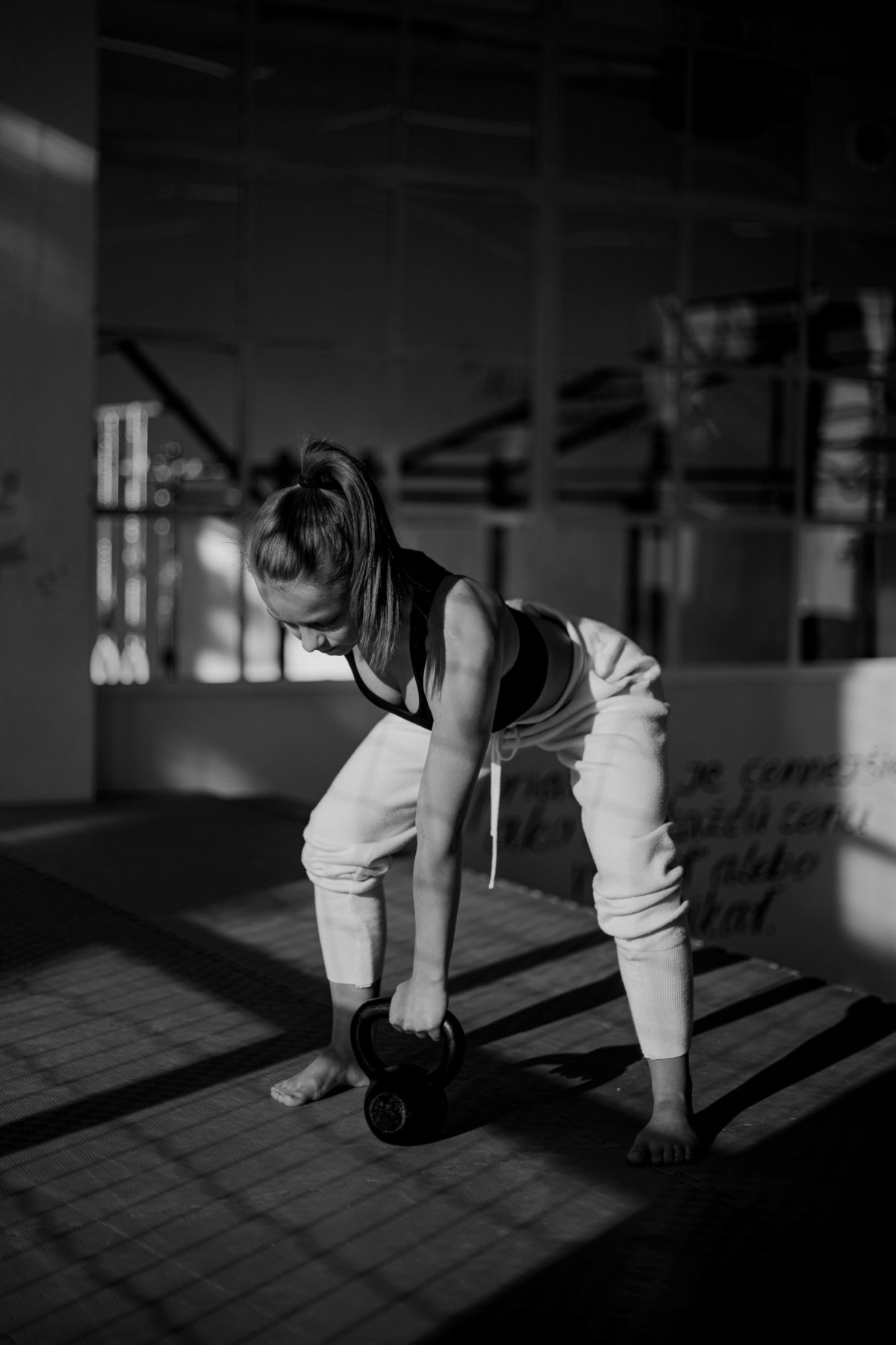 young muscular woman with workout motivation working out barefoot in the gym holding a kettlebell