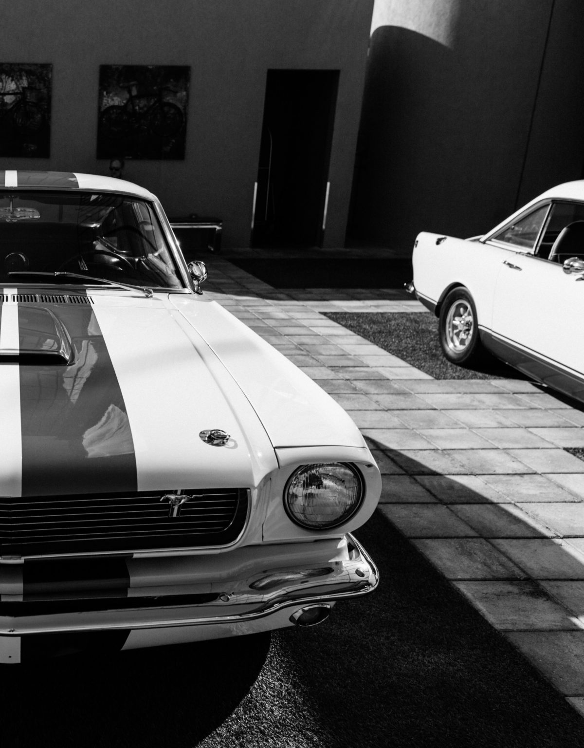 a mustang restored to perfection parked on a tiled ground next to another old car