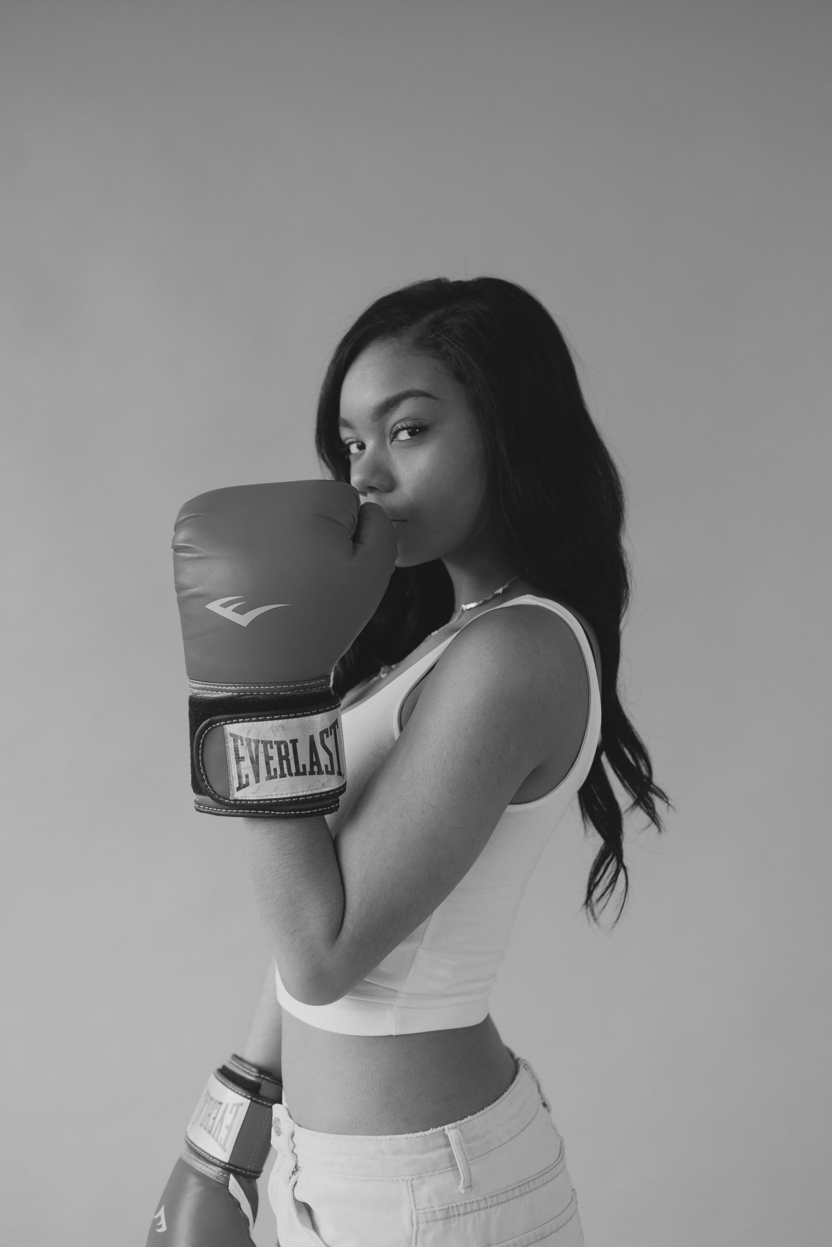 woman wearing boxing gloves showing the ugly side of crossfit on a blank background and hair out
